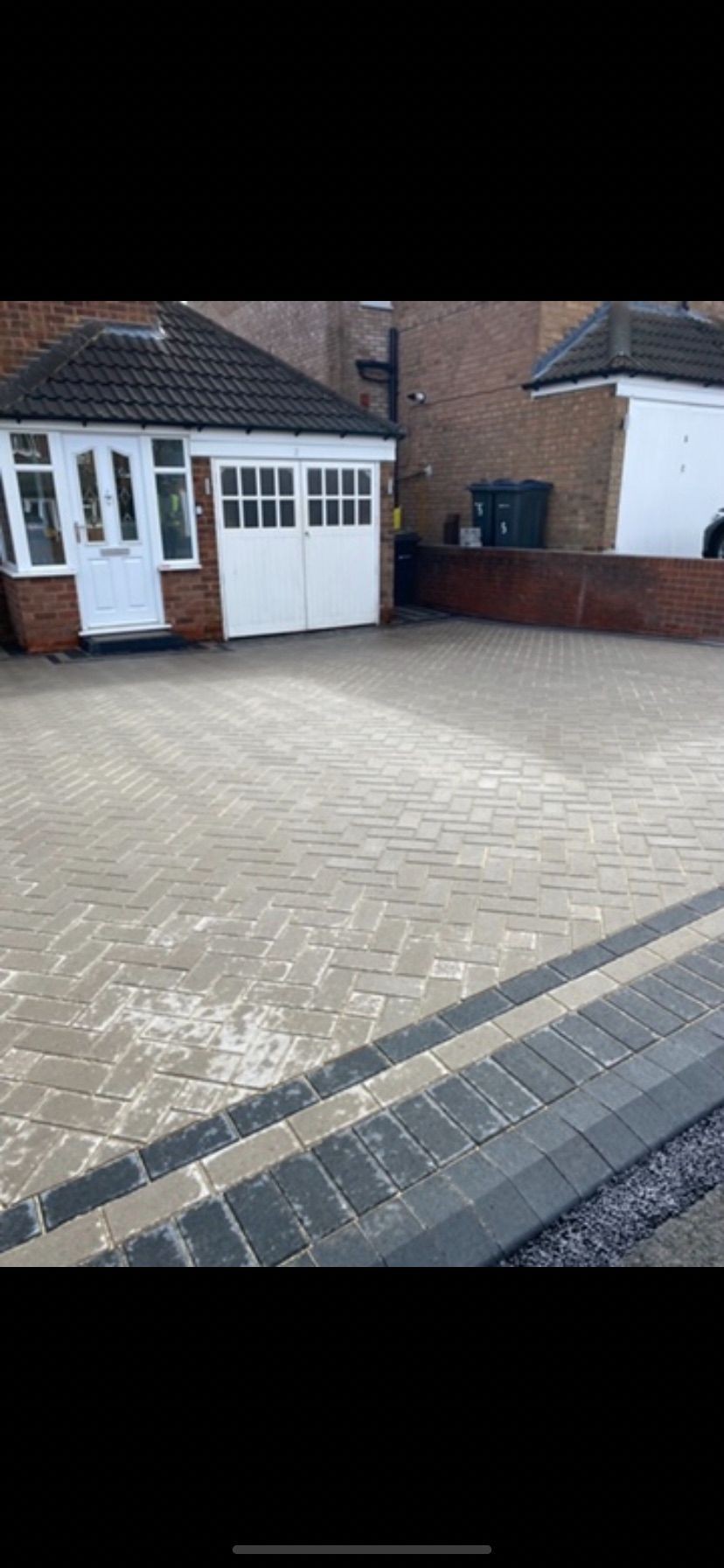 Brick-paved driveway in front of a house with a garage and a white front door.